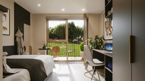A modern bedroom with a bed, a desk, and a balcony with outdoor seating. - Student Only Exchange Court (Leeds)