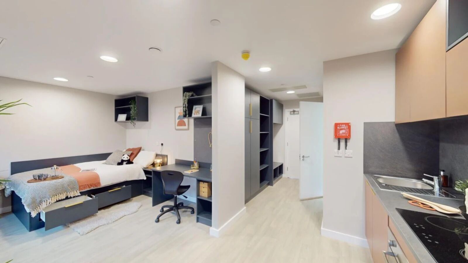 A modern bedroom with a bed, desk, and built-in shelving.