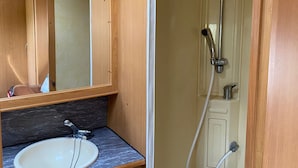 A compact bathroom with a sink, mirror, and shower. - Cozy caravan in beautiful Tornio with AC (Lappi)