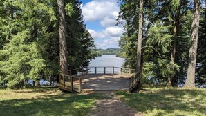 A wooden dock leading to a lake surrounded by trees. - La Chambre d'Art in the heart of nature, 300 metres from Lake St Pardoux (Saint-Pardoux-le-Lac)
