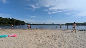 A sandy beach with people swimming and walking. - La Chambre d'Art in the heart of nature, 300 metres from Lake St Pardoux (Saint-Pardoux-le-Lac)