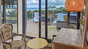Una habitación con vista al océano, una terraza de madera y una mesa con sillas.