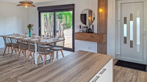 Una cocina moderna con una mesa y sillas de madera, una cafetera y un ventanal con vistas a zonas verdes.