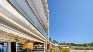 Een hotel aan de kust met een balkon, buiten zitplaatsen en uitzicht op het strand.