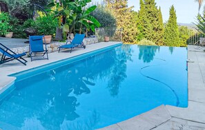 A swimming pool with blue water, surrounded by a stone patio and blue lounge chairs. - Stunning home in Speracedes (Speracedes)