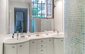 A bathroom with two sinks, a large mirror, and a window with a view of greenery. - Stunning home in Speracedes (Speracedes)
