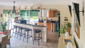 A spacious kitchen with a central island, bar stools, and a dining area with a table and chairs.