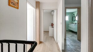 Ein Flur mit Holztür, Treppe und Blick ins Badezimmer mit Spiegel und Waschbecken.