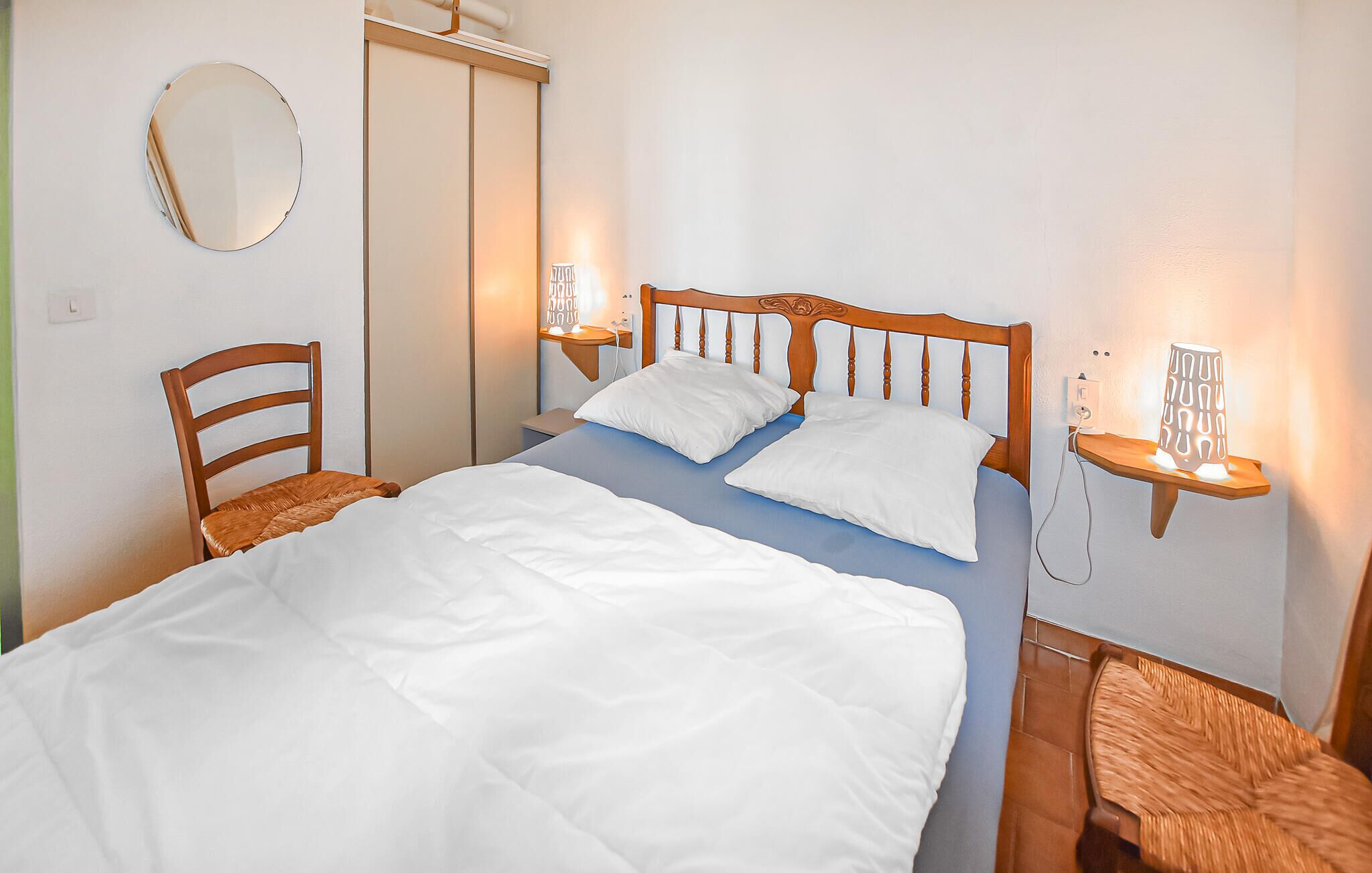 A neatly made bed with white linens, a wooden headboard, and two bedside tables with lamps.