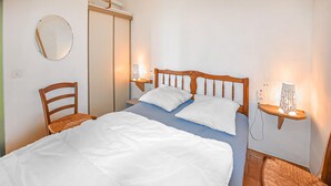 A neatly made bed with white linens, a wooden headboard, and two bedside tables with lamps. - 2 bedroom lovely home in Villars (Villars)