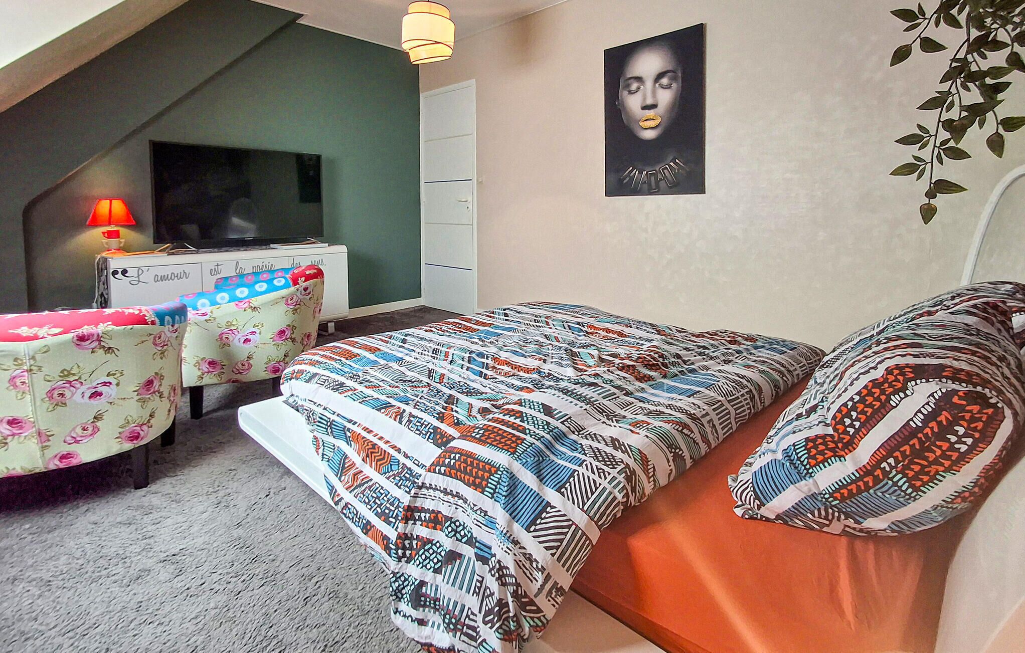 Une chambre à coucher avec un lit, un bureau, une chaise, un téléviseur et une affiche accrochée au mur.