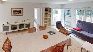 Amplia sala de estar con una mesa de comedor, sillas, un sofá y una estantería.