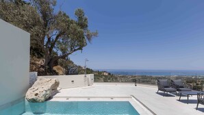 A swimming pool with a view of the sea, outdoor seating, and a large rock. - Santa Irini Villas - With 3 Heated Pools (Agia Eirini)
