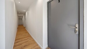 Un pasillo con suelo de madera que conduce a una puerta gris con el número 1.