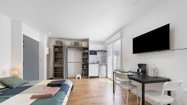 A bedroom with a bed, bedside table, and a TV mounted on the wall. - Studio '4' with Private Terrace, Shared Garden, SPA and Wi-Fi (Hanvec)