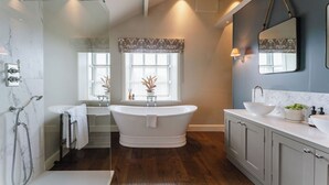 A bathroom with a freestanding bathtub, a double sink vanity, and a shower area. - Three Acres Inn & Restaurant (Huddersfield)