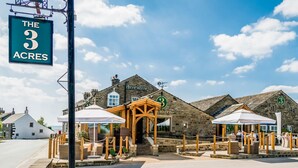 A building with a sign reading "The 3 Acres" and a wooden entrance with a sign for "L Roger Room". - Three Acres Inn & Restaurant (Huddersfield)