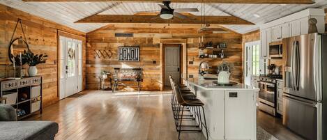 A spacious kitchen with wooden walls, a central island, and modern appliances.