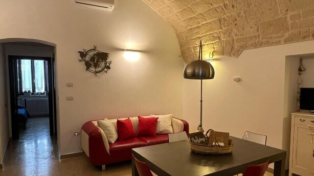 Un salon chaleureux avec un canapé rouge, une table à manger et une lampe.