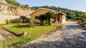 Una casa amarilla con un muro de piedra y un jardín.