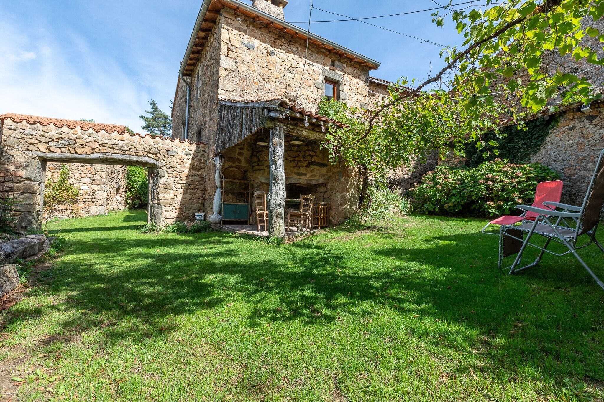 Un bâtiment en pierre doté d’une arche en pierre, d’une porte en bois et d’une chaise rouge placée à l’extérieur.