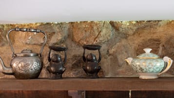 A shelf with three tea sets against a stone wall.