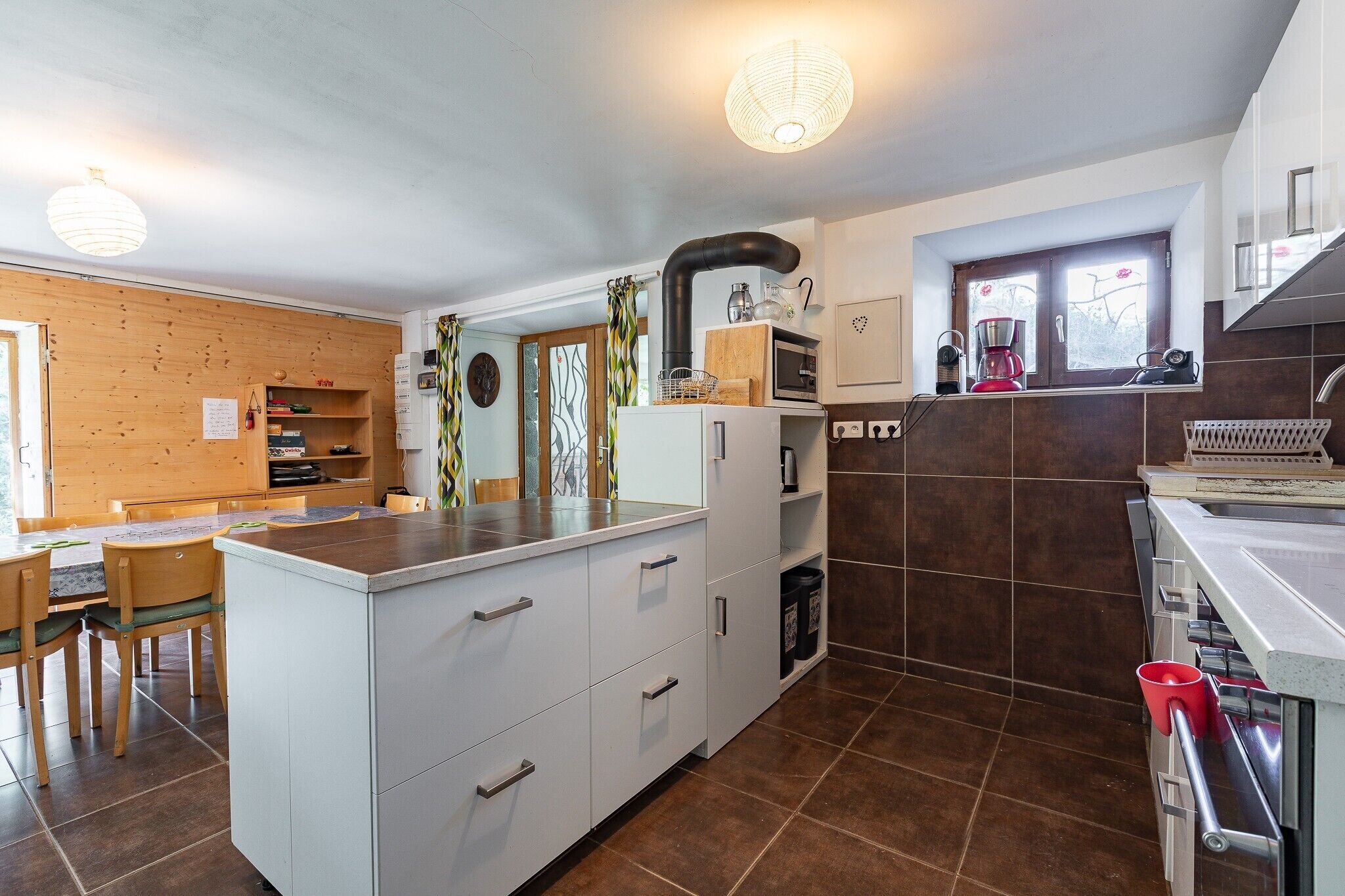Una cucina moderna con isola centrale, elettrodomestici integrati e zona pranzo con sedie in legno.