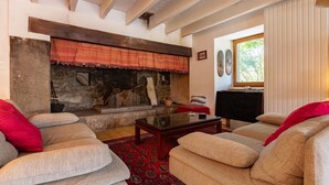 A living room with a stone fireplace, sofas, a coffee table, and a television. - Country House 'La Gabbro' with Mountain View, Private Terrace and Wi-Fi (Saint-Barthélemy-Grozon)
