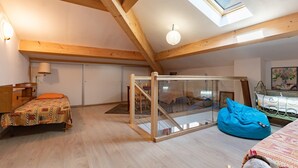 A room with a sloped ceiling, wooden beams, a skylight, a bed, a bean bag, a desk, and a wardrobe. - Country House 'La Gabbro' with Mountain View, Private Terrace and Wi-Fi (Saint-Barthélemy-Grozon)