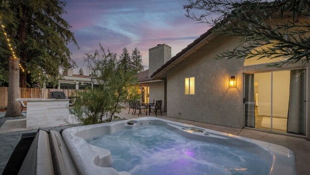 Ein Whirlpool in einem Hinterhof mit einer Holzterrasse, einem Patio-Tisch und Stühlen.