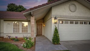 Ein Wohnhaus mit Garage, Haustür und einem kleinen Garten mit Blumen und Sträuchern.