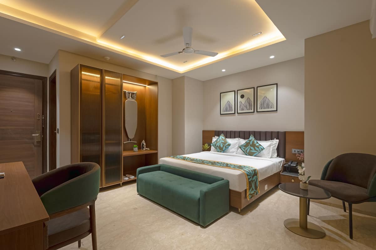 Une chambre d’hôtel moderne équipée d’un lit, d’un bureau, d’une chaise, d’un canapé et d’un ventilateur de plafond.