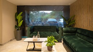 A modern interior with a green sofa, a white table, and potted plants. - Saltstayz Premier Naraina Central Delhi (New Delhi)