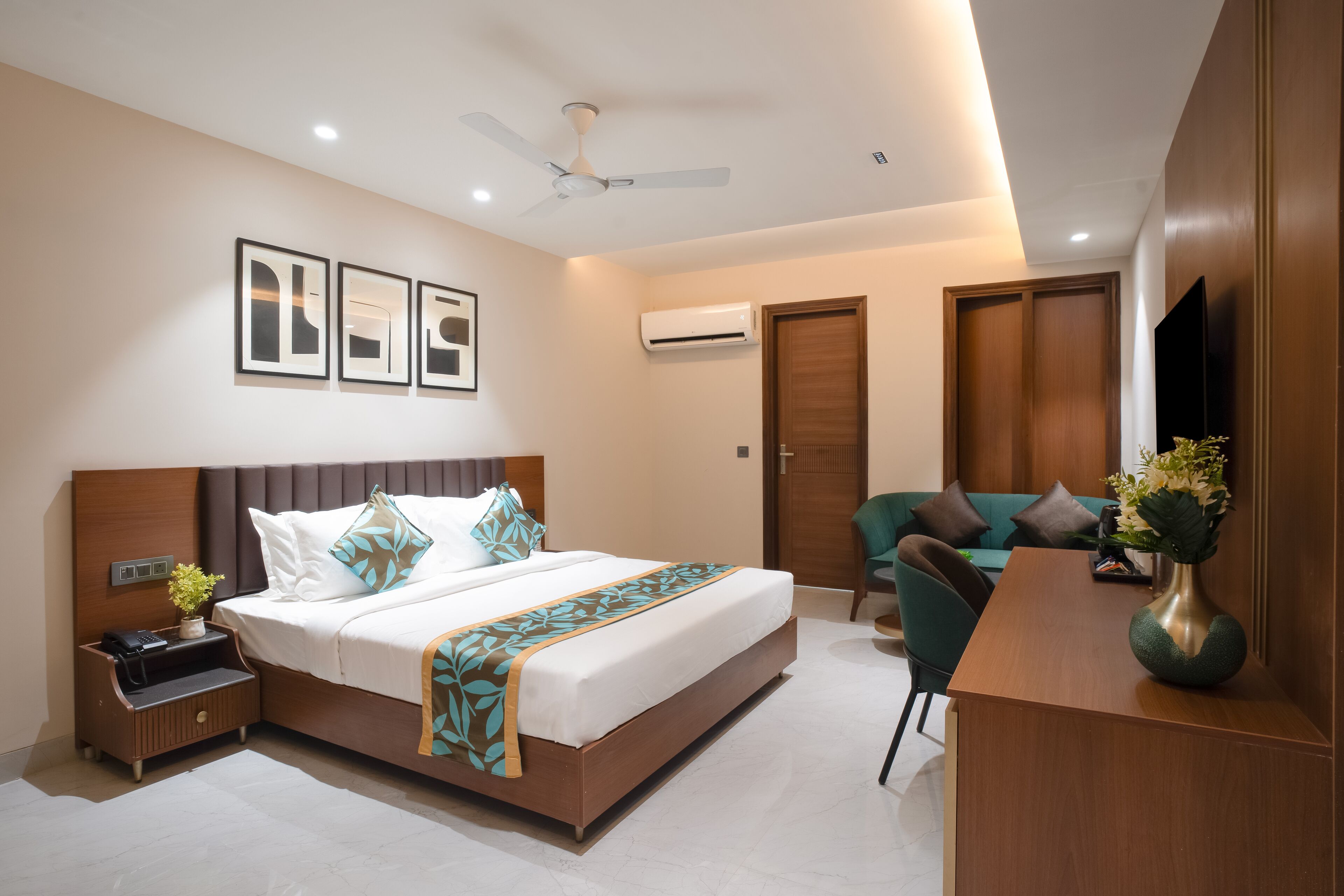 A modern hotel room with a large bed, a desk, a chair, and a TV.