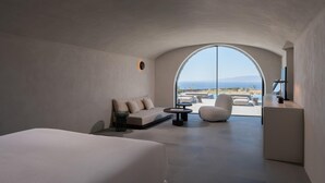 A modern bedroom with a large arched window, a sofa, a bed, and a desk area. - Villa Kallisti with private pool - My Rental Homes (Ia)