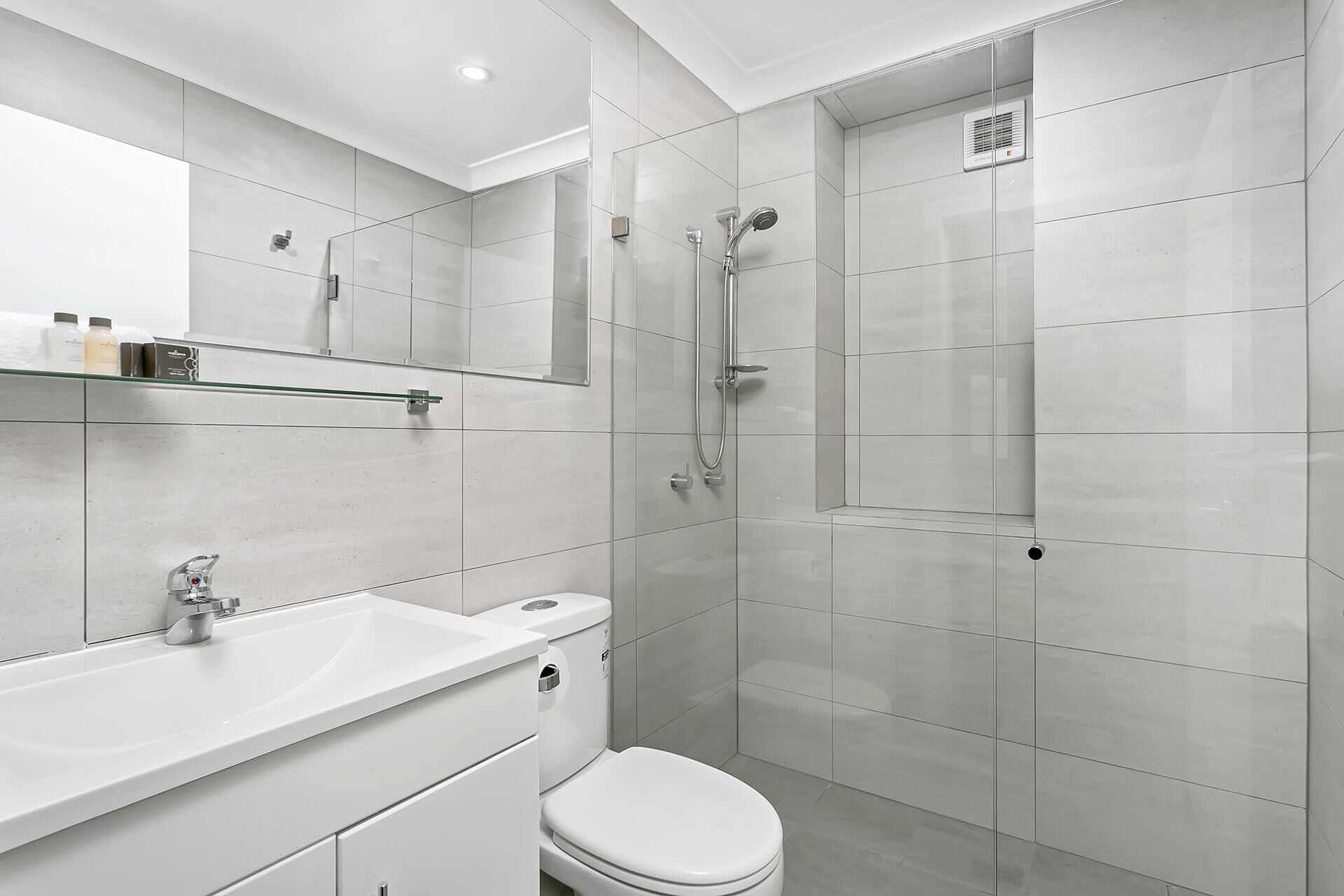 A modern bathroom with a white sink, toilet, and shower.