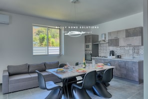A modern kitchen with grey cabinets, a dining table with chairs, and a sofa. - Villa Stella with private pool 500 mt from the sea By Sicily Home Solutions (Sicilia)