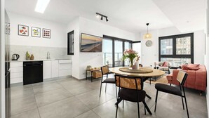 A modern kitchen with white cabinets, a black dishwasher, and a dining area with a round table and chairs.