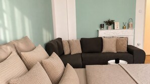 Ein Wohnzimmer mit einer Couch, mehreren Kissen, einem Couchtisch und einem Kamin mit Dekorationen.