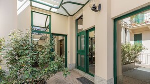 A building entrance with a glass door, a potted plant, and a metal grate. - Lofts Cit Turin by Wonderful Italy (Turin)