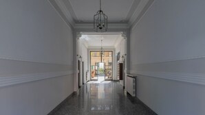 A long, narrow hallway with polished granite floors and white walls, leading to a bright, open space with a view of the outside. - Lofts Cit Turin by Wonderful Italy (Turin)