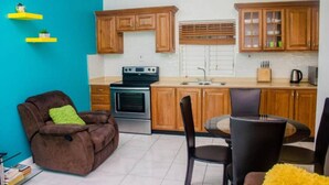 A compact kitchen with wooden cabinets, a built-in oven, and a dining area with a table and chairs.