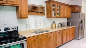 A kitchen with wooden cabinets, a stainless steel refrigerator, a microwave, and a stove.
