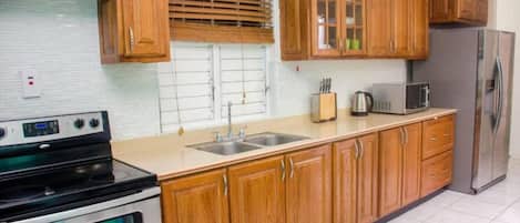 A kitchen with wooden cabinets, a stainless steel refrigerator, a microwave, and a stove.