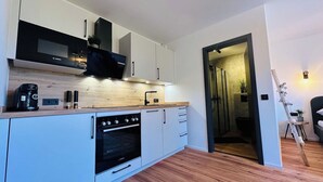 Una cocina moderna con armarios blancos, un horno Bosch y una cafetera.