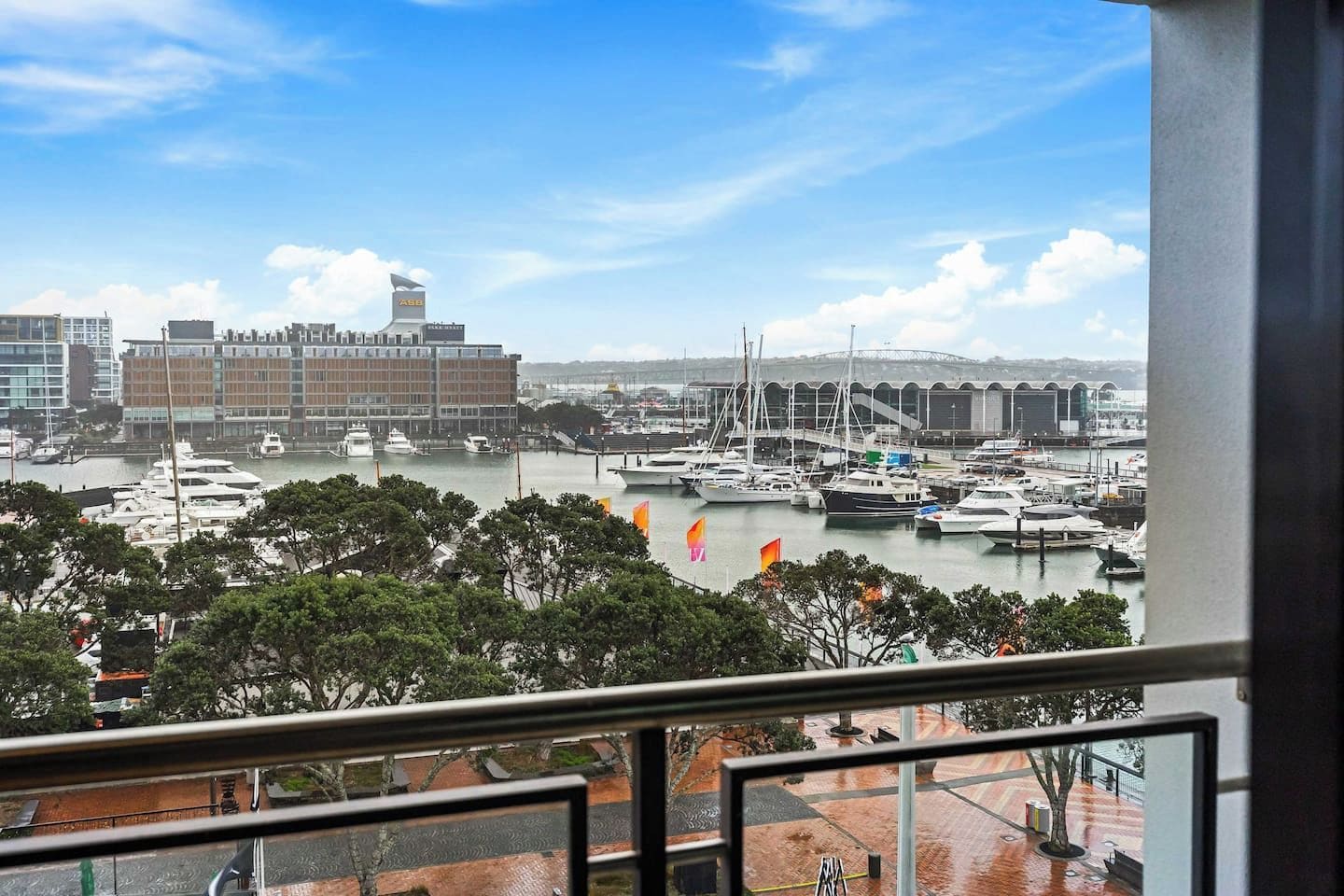 A marina with boats, a large building with 'ABB' sign, and a view of the cityscape.