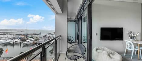 A balcony with a view of a marina, a flat-screen TV, and modern furniture.