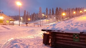 A snow-covered ski resort at dusk with illuminated pathways and a wooden cabin. - Riverfront Cottageee (Äänekoski)