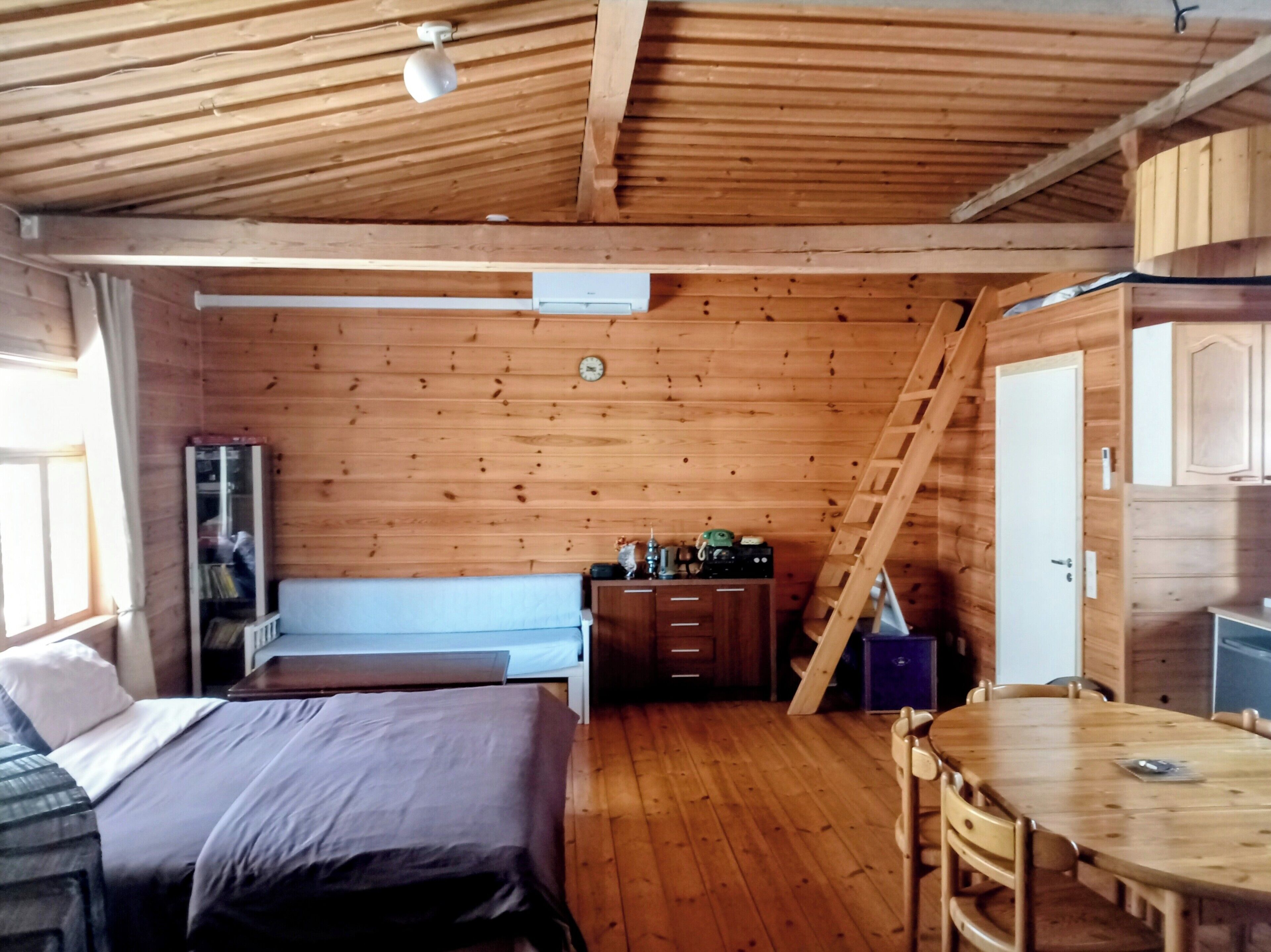 A wooden cabin with a loft bedroom, a dining area, and a kitchen.