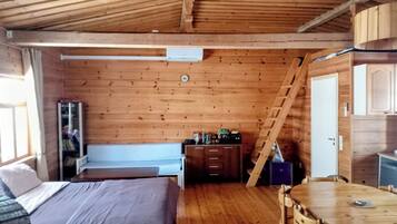 A wooden cabin with a loft bedroom, a dining area, and a kitchen.